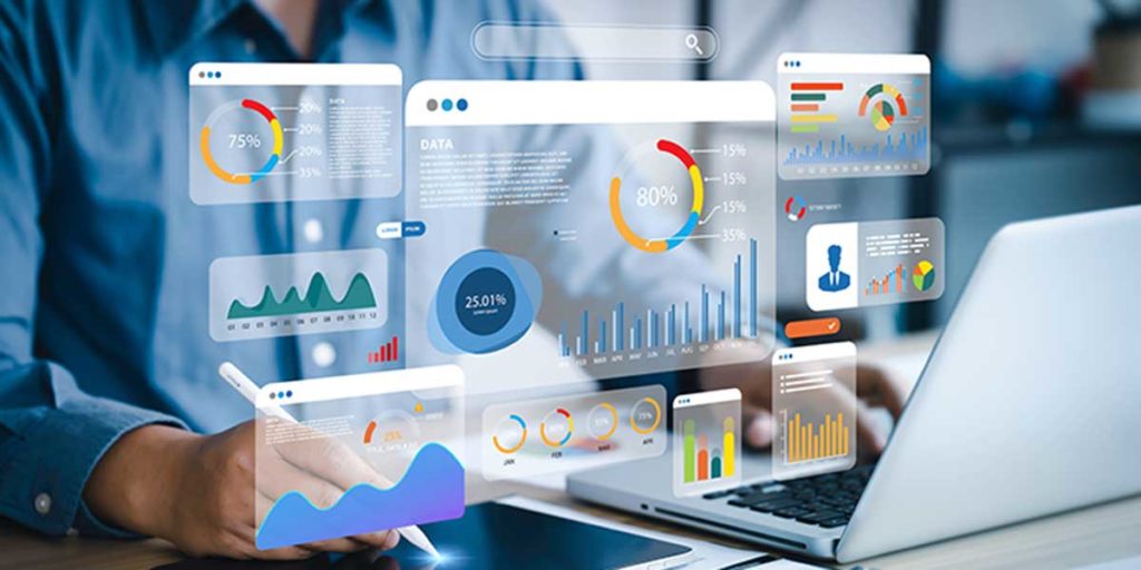 A business professional analyzing data on a tablet and laptop, surrounded by digital analytics dashboards with charts, graphs, and percentages. Credit: Shutterstock